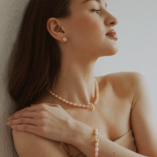 Minimalistische Perlenohrringe: Zeitlose Eleganz im Set mit vergoldeter Perlenkette und -armband. Entdecken Sie hochwertigen Schmuck für einen subtilen Look!